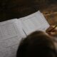child writes on his book on the desk
