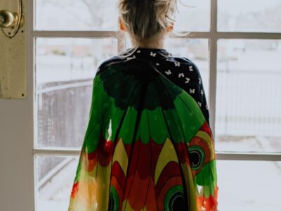 childin green orange and yellow dress standing near window