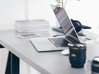 silver MacBook Pro on white desk with coffee cup and phone