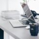 silver MacBook Pro on white desk with coffee cup and phone