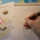 a person writing on a notebook with a pen