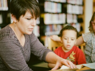 woman in gray long sleeve shirt sitting beside boy in orange crew neck shirt