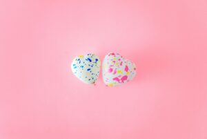 two speckled-coloured heart-shaped balloons on pink background