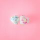 two speckled-coloured heart-shaped balloons on pink background