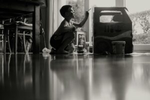 young boy sitting on floor at home painting something