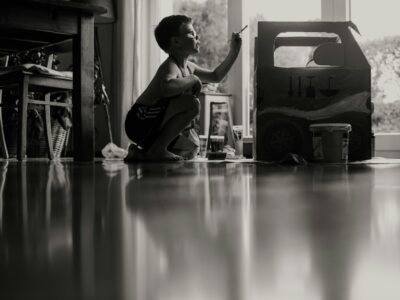 young boy sitting on floor at home painting something