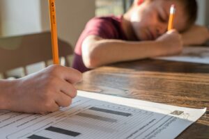 two children writing on paper at table in home
