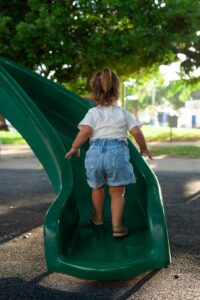 a little girl playing on a green slide
