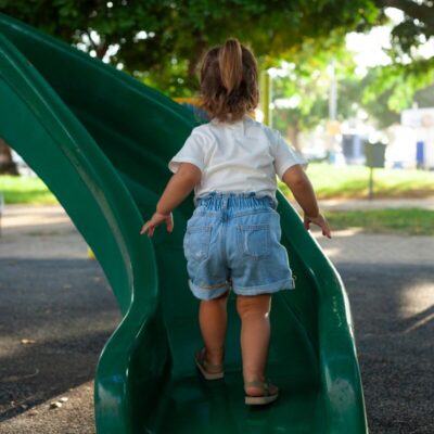 a little girl playing on a green slide