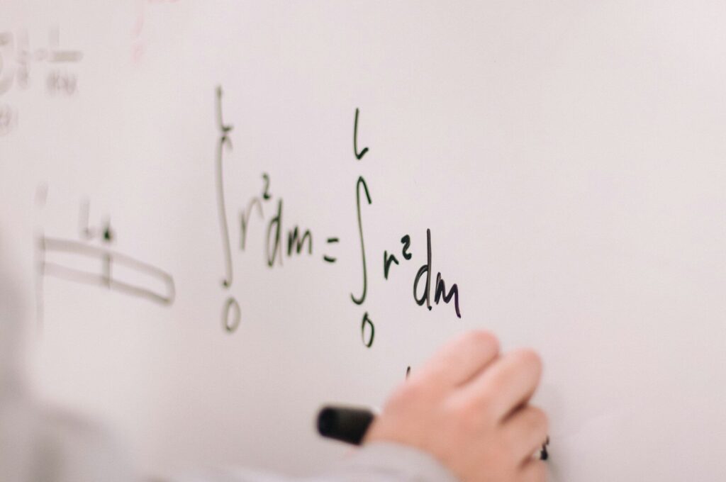 person writing maths on a whiteboard