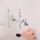person writing maths on a whiteboard