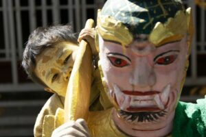 Child peeking from behind a colourful mask