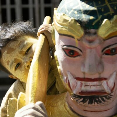 Child peeking from behind a colourful mask
