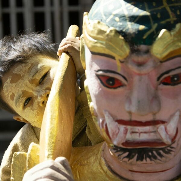 Child peeking from behind a colourful mask